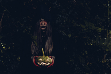 Portrait of woman ghost horror her have pumpkin on hand in forest, halloween day conceptの写真素材