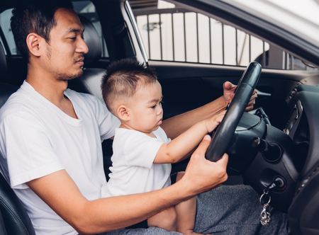 Dad driving car with baby sitting on the lap, father and sonの写真素材