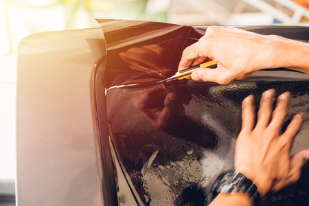 Man specialist service attached window film by cutter on carの写真素材