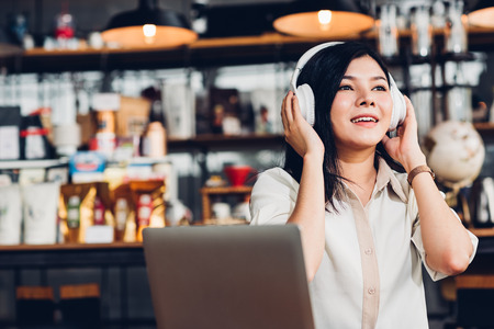 Lifestyle freelance woman he using earphones listening music during working on laptop computer in coffee shopの写真素材