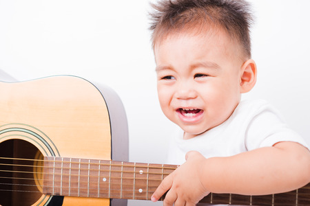 Asian portrait child boys 1 year 6 months playing guitar on white backgroundの写真素材