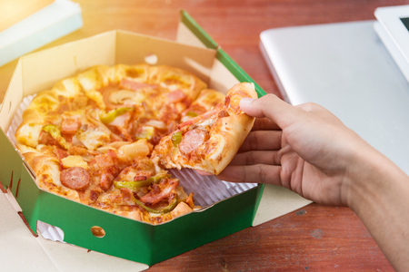 Hands taking pizza slices from green boxの写真素材