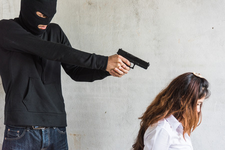 The robber thief man point gun to head is about to kill the women female hostage, crimeの写真素材