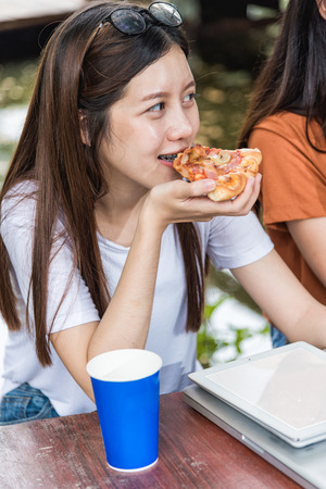 Portrait asian woman students eating pizza with cheese delicious at outdoor university, Education conceptの写真素材