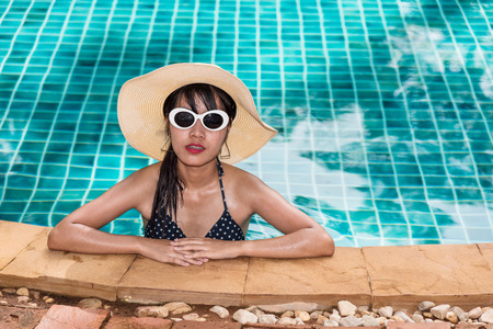 Beautiful woman model in bikini and sunglasses fashion relaxing in resort, summer swimming pool water on holidaysの写真素材