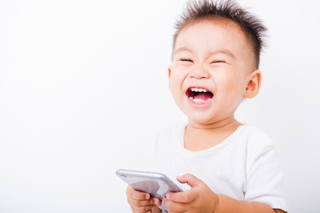 Asian portrait child boys 1 year 6 months expression Laugh glad for touch smartphone on hand on white backgroundの写真素材