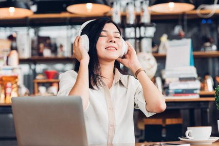 Lifestyle freelance woman he using earphones listening music during working on laptop computer in coffee shopの写真素材