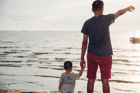 Baby boy son and father dad lifestyle happiness pointing to sea beach in vacation holidayの写真素材