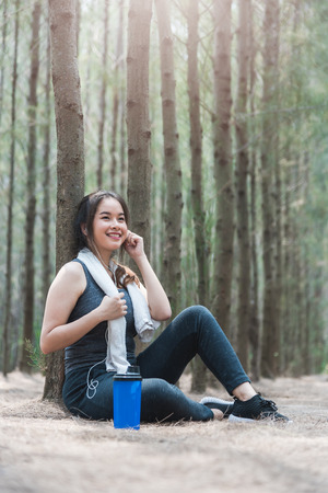 Beautiful sport young woman girl lifestyle exercise healthy break drinking water from bottle after running workout in forest nature park with copy spaceの写真素材