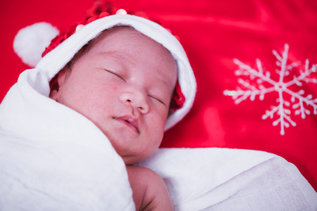 Newborn baby sleeping on santa het and red background, christmas or happy new year conceptの写真素材
