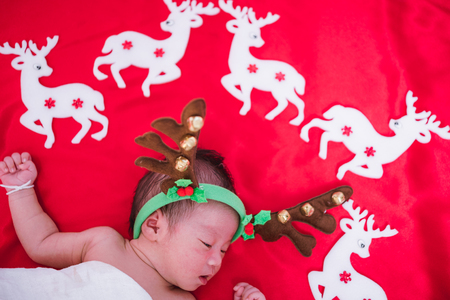 Newborn baby girl sleeping with deer, christmas or happy new year conceptの写真素材