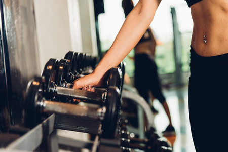 Hand of woman weights dumbbell equipment at fitness gym