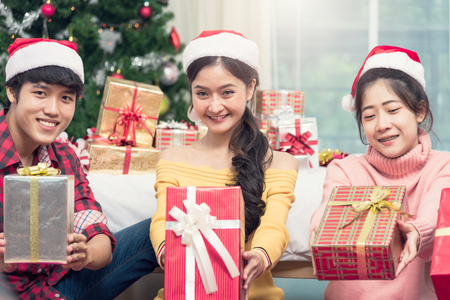 Group of friends celebrating showing gift box Christmas at homeの写真素材