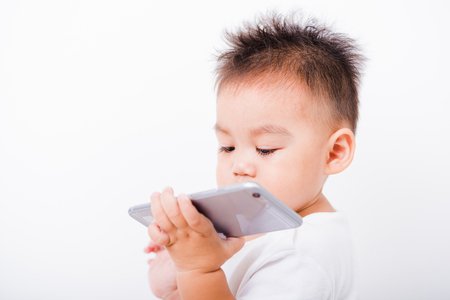 Asian portrait child boys 1 year 6 months holding smartphone on hand on white backgroundの写真素材
