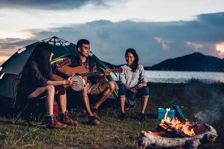 Camping tent camp in nature happy friends group night party bonfire and playing guitar together in summer at nature forestの写真素材