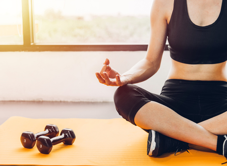 Beautiful woman sitting yoga on hands after exercise workout at fitness GYMの写真素材
