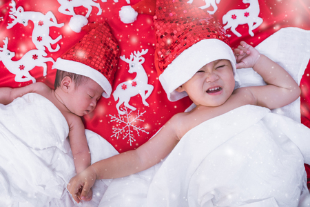 Child boy brother and sister girl newborn baby infant have santa red hat, christmas or happy new year conceptの写真素材