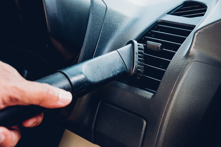 Worker man cleaning dust interior vacuum inside car after washの写真素材