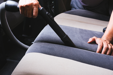 Worker man cleaning dust interior vacuum inside car after washの写真素材