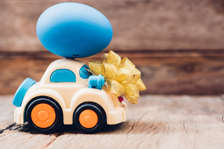 Easter egg and toy car on wooden background, happy easter day conceptの写真素材