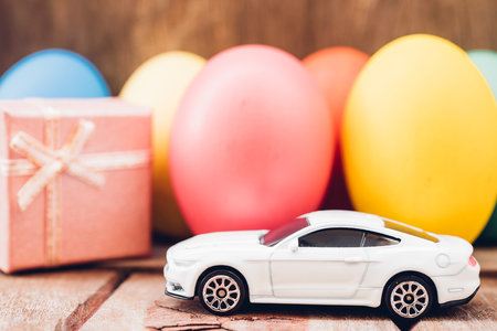 Easter egg and toy car on wooden background, happy easter day conceptの写真素材