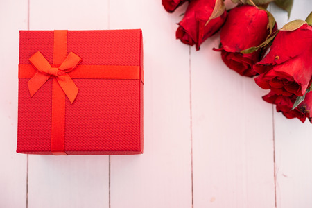 Red flower roses and gift box on white wooden background, valentine day conceptの写真素材