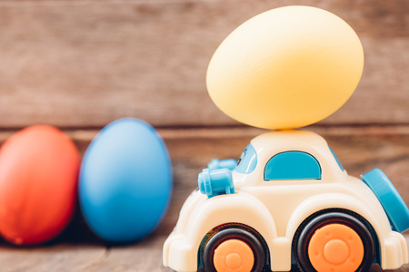 Easter egg and toy car on wooden background, happy easter day conceptの写真素材