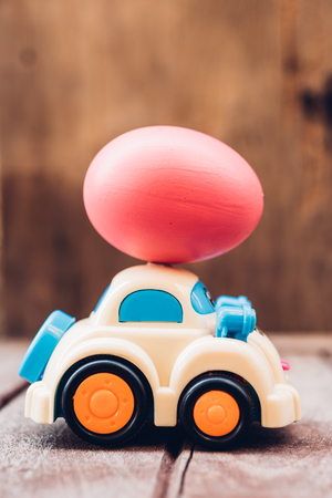 Easter egg and toy car on wooden background, happy easter day conceptの写真素材