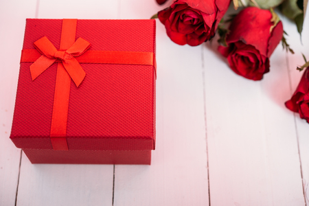 Red flower roses and gift box on white wooden background, valentine day conceptの写真素材
