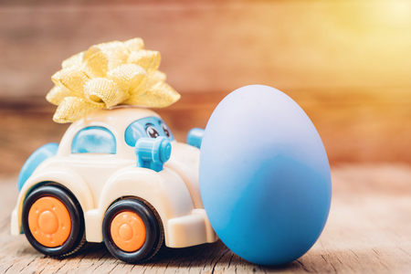 Easter egg and toy car on wooden background, happy easter day conceptの写真素材