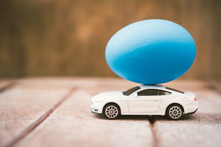 Easter egg and toy car on wooden background, happy easter day conceptの写真素材