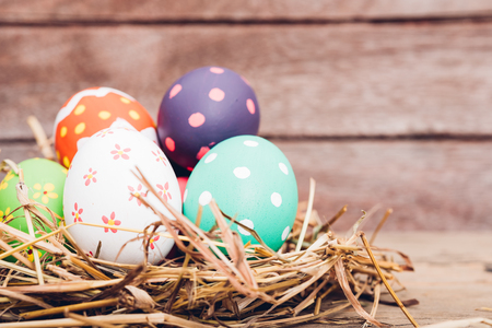Beautiful Easter multi color egg in straw on wooden background, Easter day conceptの写真素材