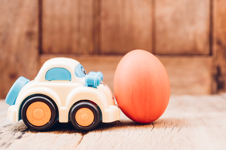 Easter egg and toy car on wooden background, happy easter day conceptの写真素材