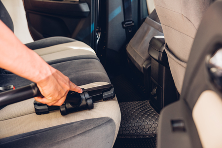 Worker man cleaning dust interior vacuum inside car after washの写真素材