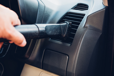 Worker man cleaning dust interior vacuum inside car after washの写真素材