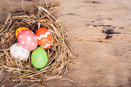 Beautiful Easter multi color egg in straw on wooden background, Easter day conceptの写真素材