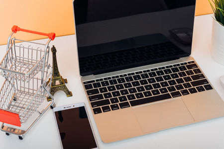 Mock up laptop notebook computer and shoppong online cart on desk table office soft yellow wallの写真素材