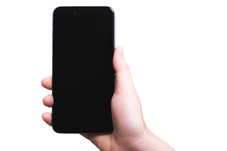 Female hand holding smartphone plus blank black screen isolated on over white backgroundの写真素材