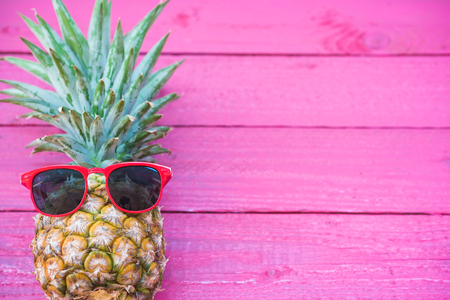 Holiday pineapple have sunglasses on pink    wooden background, tropical holiday conceptの写真素材