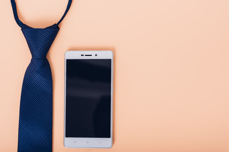 Business necktie and smartphone on soft yellow desk tableの写真素材