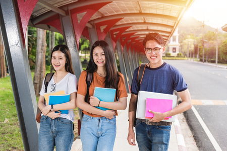 Male and female students stand on books and laptop computers on campus, Education conceptの写真素材