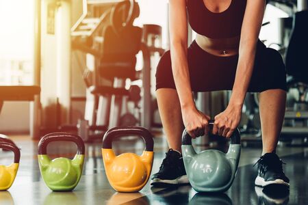 Beautiful woman using dumbbell weights workout at fitness GYMの写真素材