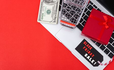 Online shopping, Promotion Black Friday Sale text on black tag with computer laptop and money on red...