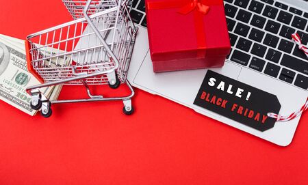Online shopping, Promotion Black Friday Sale text on black tag with computer laptop and money on red background.の写真素材