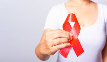 Closeup of female with red ribbon HIV AIDS on hand, World AIDS Day and medicine conceptの写真素材