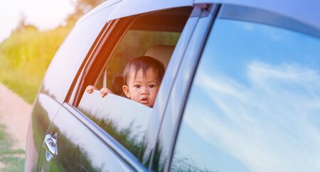 Asian little baby girl traveling looking out from windows car on nature summerの写真素材