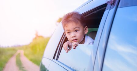 Asian little kid boy traveling looking out from windows car on nature summerの写真素材