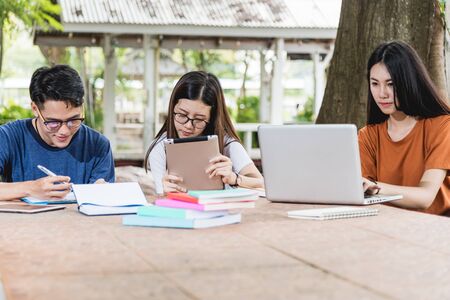 Man students and girlfriend are consult information from computer laptop, tablet and book outdoor,...