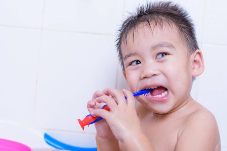 Portrait asian kid brushes teeth with toothpaste on mouth every day after he shower on white wallの写真素材