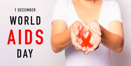 Closeup of female with red ribbon Support HIV AIDS on hands, World AIDS Day and medicine concept...